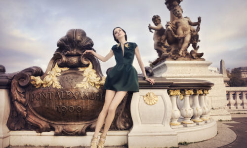 A young woman dressed in a haute couture dress posing on the Pont Alexandre 3 bridge in Paris