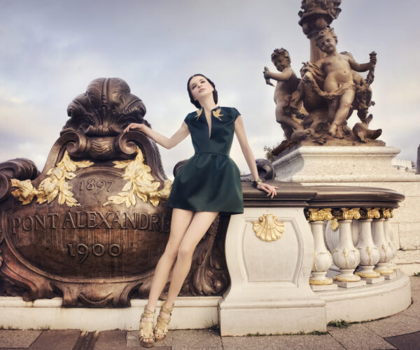 A young woman dressed in a haute couture dress posing on the Pont Alexandre 3 bridge in Paris