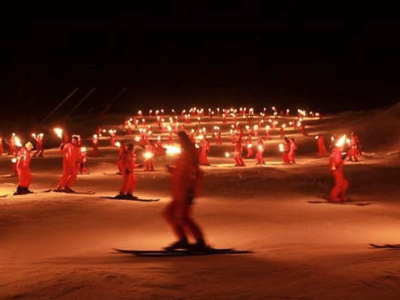 Skiers coming down a mountain at night with lit torches “Descente en flambeaux”