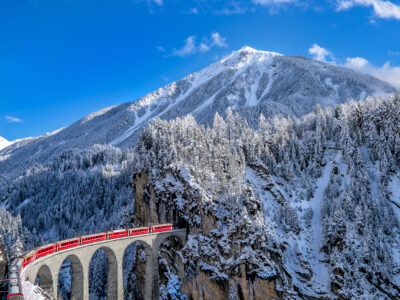 train running from one mountain to another with snow cap mountain