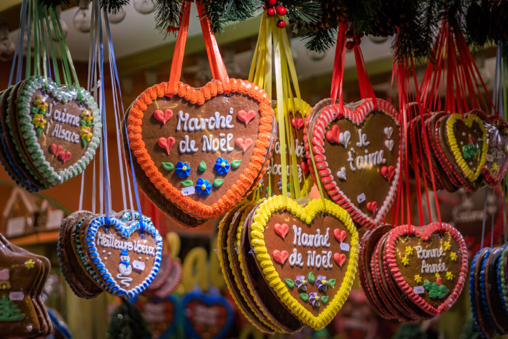 Traditional Alsace Christmas market food featuring warm gingerbread, bredele biscuits, mulled wine, festive pastries, and regional holiday specialties served in a cozy winter atmosphere.
